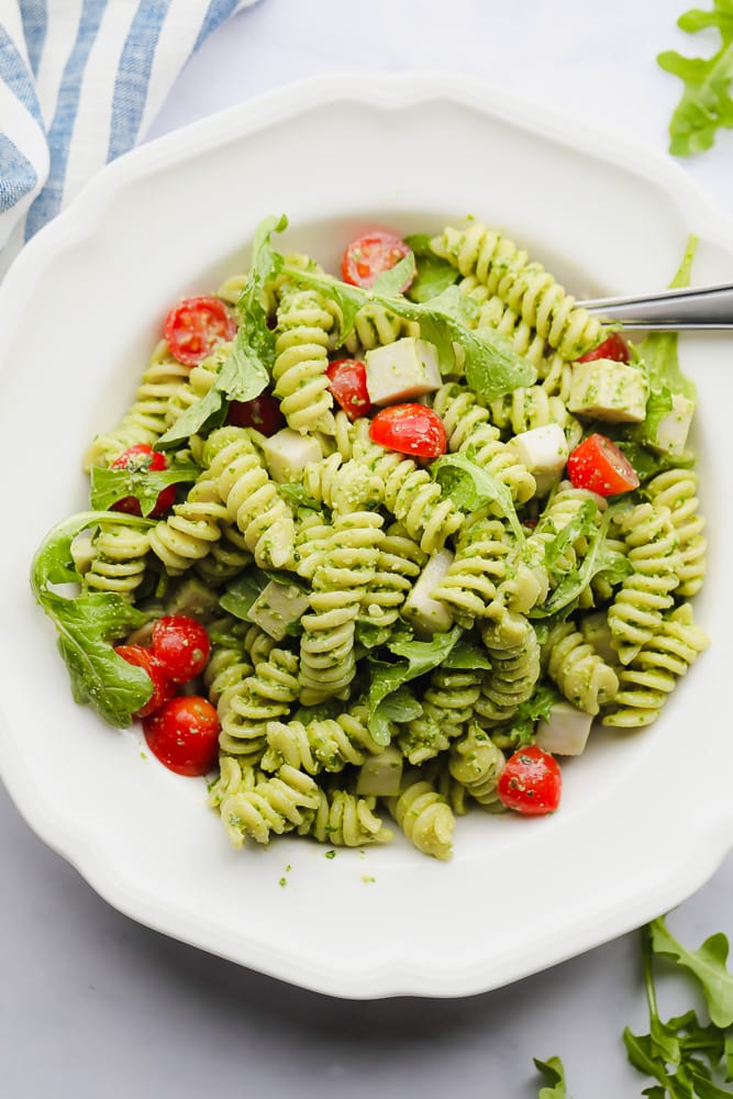 pesto pasta salad with tomatoes in a white bowl