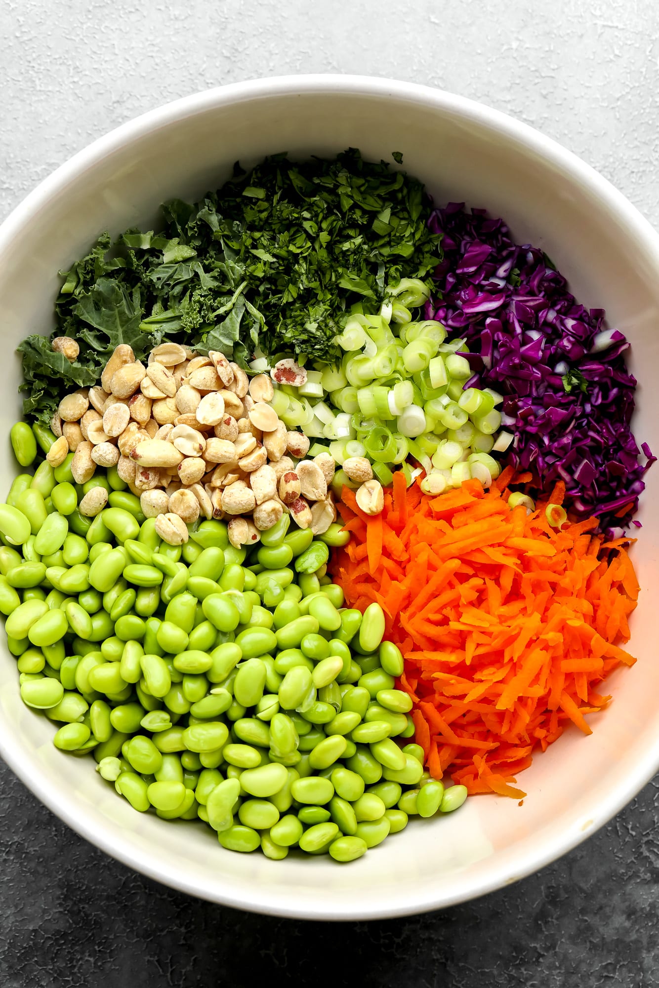 ingredients for edamame salad in a large white bowl.