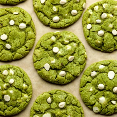 close up on green white chocolate chip matcha cookies on a layer of parchment paper.