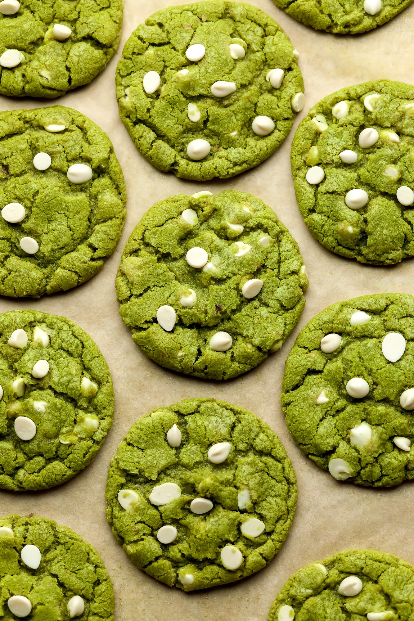 green white chocolate chip matcha cookies on a layer of parchment paper.