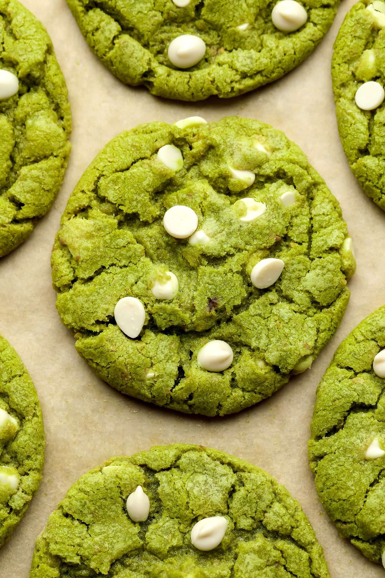 close up on a green white chocolate chip matcha cookie on a layer of parchment paper.