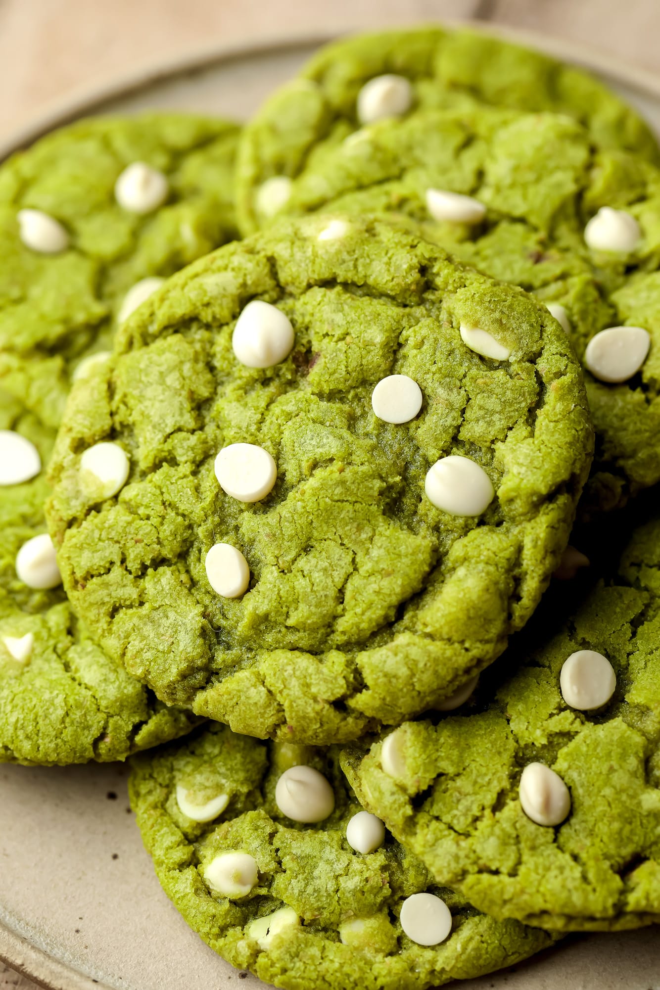 a pile of green white chocolate chip matcha cookies on a plate.