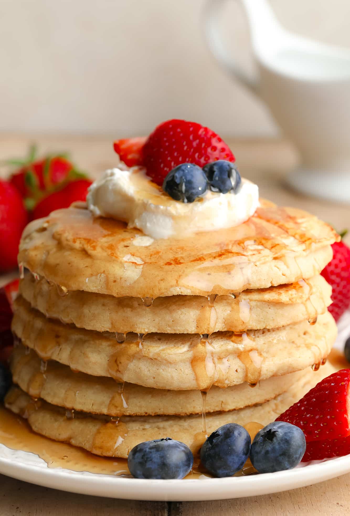 a stack of vegan oat flour pancakes with butter and berries on top.