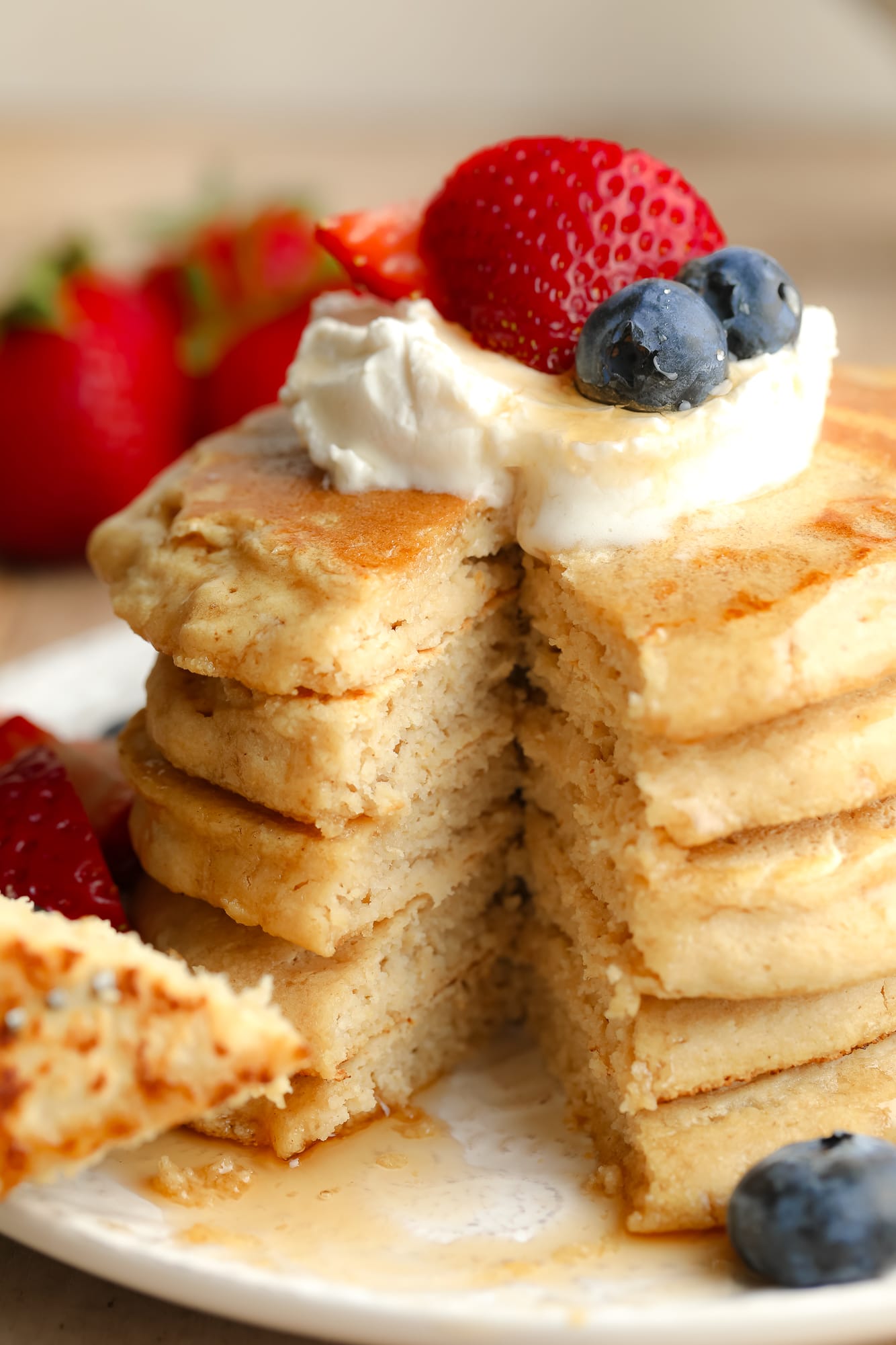 a stack of vegan oat flour pancakes with butter and berries on top.
