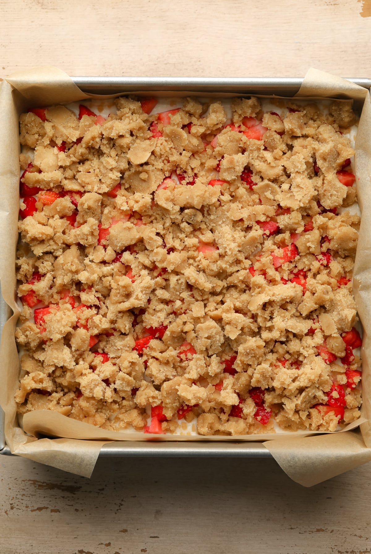 an unbaked batch of Vegan Strawberry Cheesecake Crumble Bars in a square baking tin.