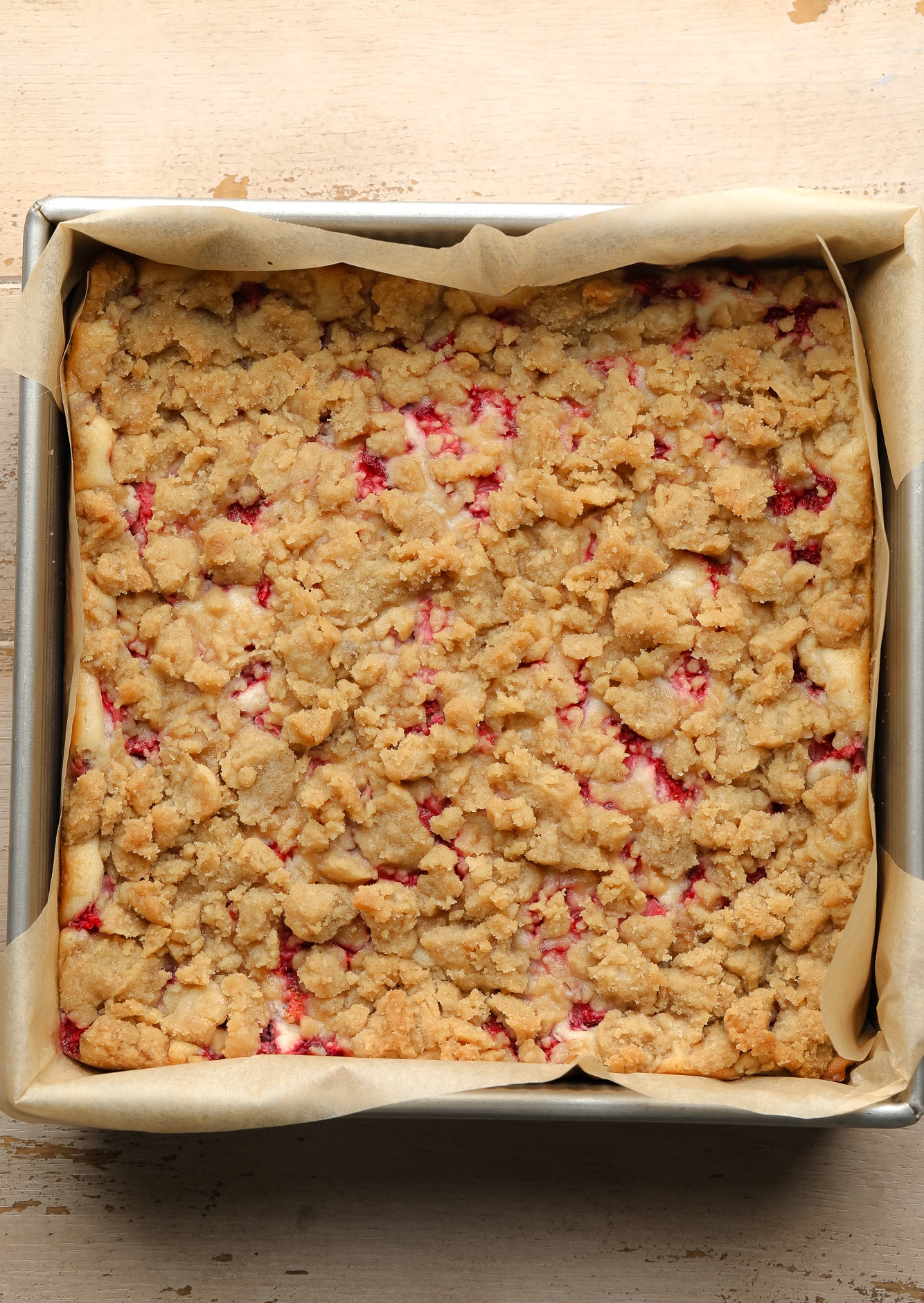 an baked batch of Vegan Strawberry Cheesecake Crumble Bars in a square baking tin.