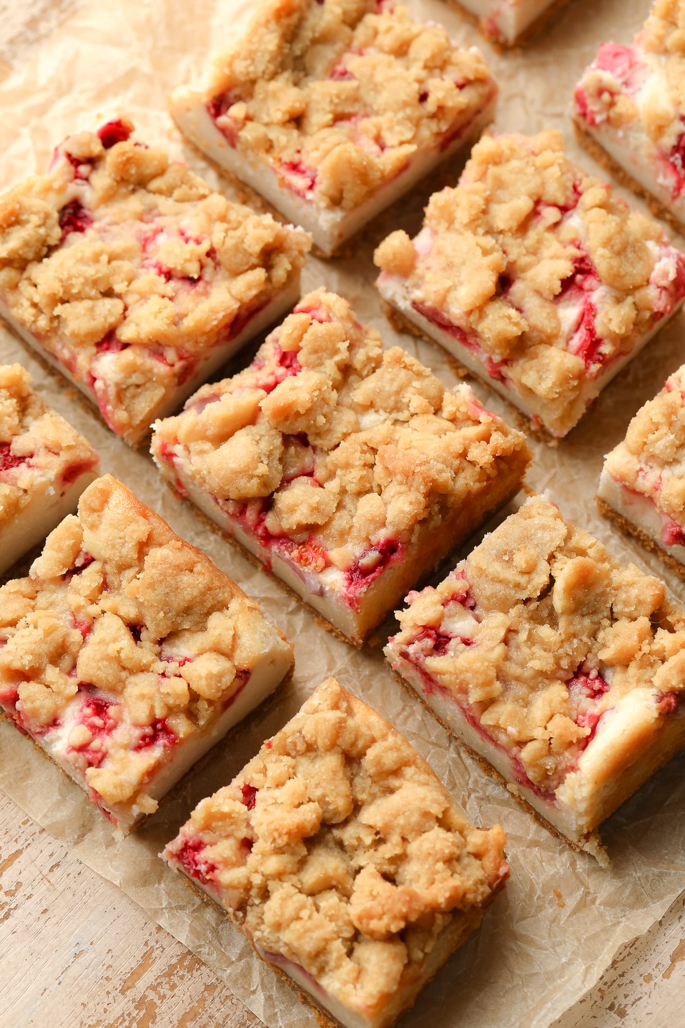 sliced Vegan Strawberry Cheesecake Crumble Bars on a piece of parchment paper.
