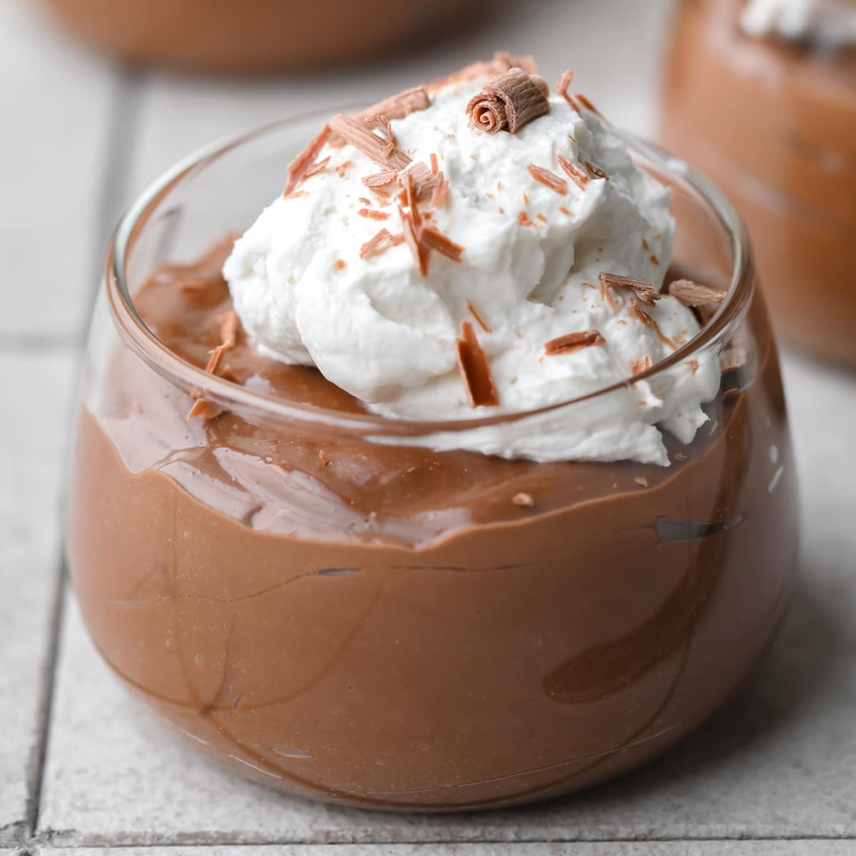close up on tofu chocolate mousse topped with whipped cream in a glass jar.