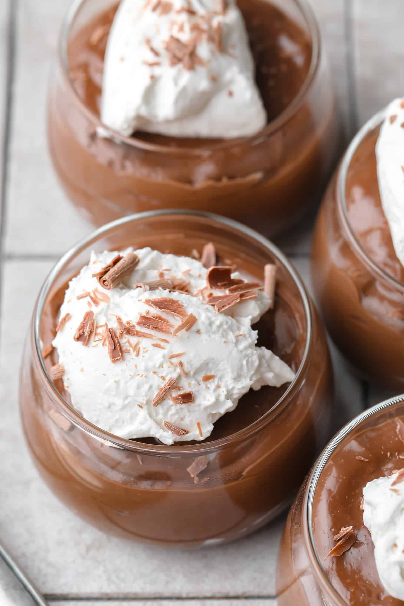 tofu chocolate mousse topped with whipped cream in glass jars.