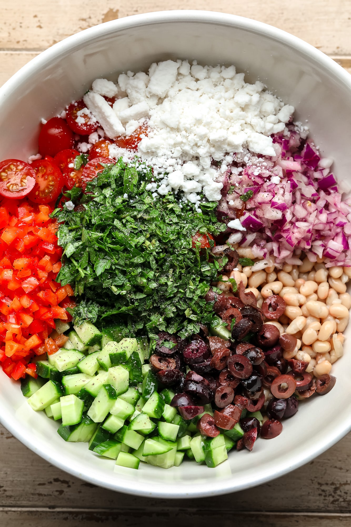 the ingredients for white bean salad in a large white bowl.