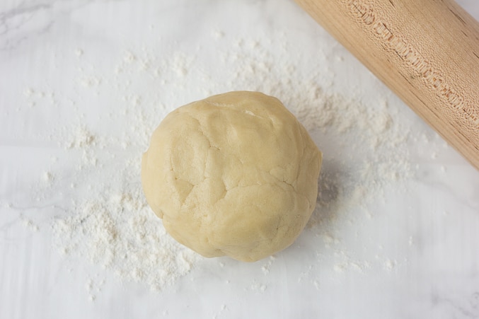 a ball of sugar cookie dough on a floured surface.
