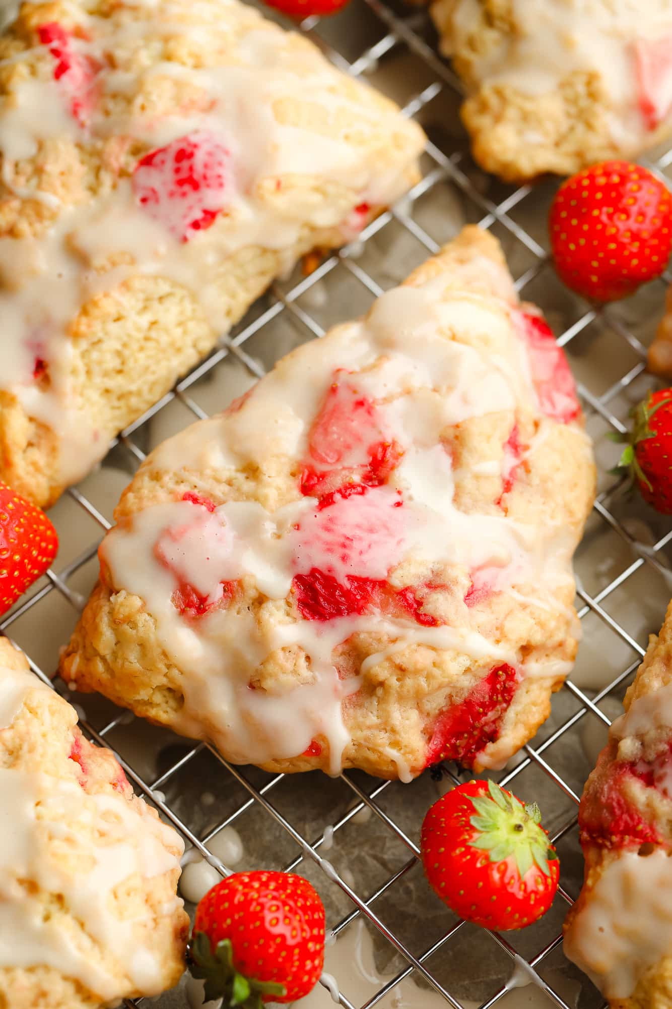 close up on a baked strawberry scone topped with vanilla glaze.