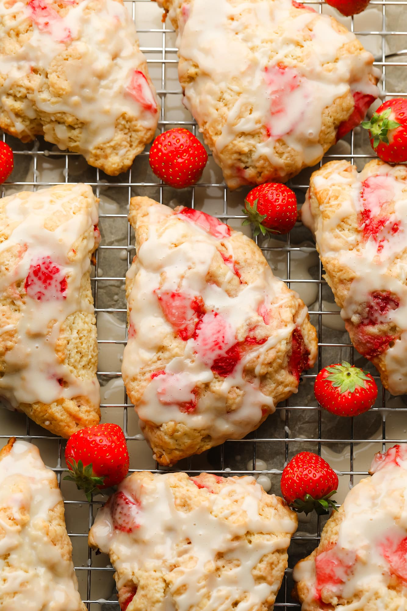 baked strawberry scones topped with vanilla glaze on a wire rack.
