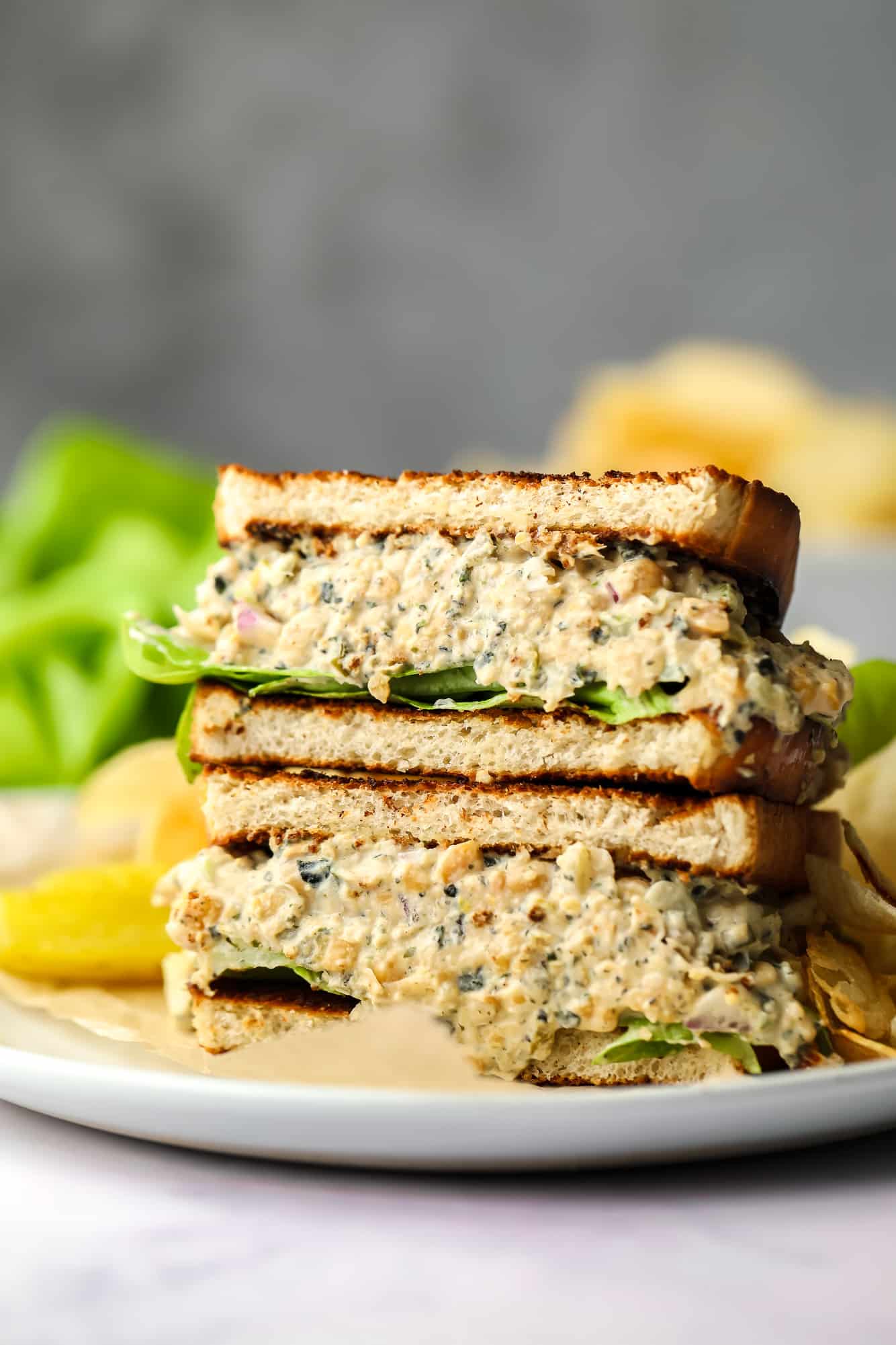 vegan chickpea tuna salad sandwich with butter lettuce stacked on plate showing thick filling