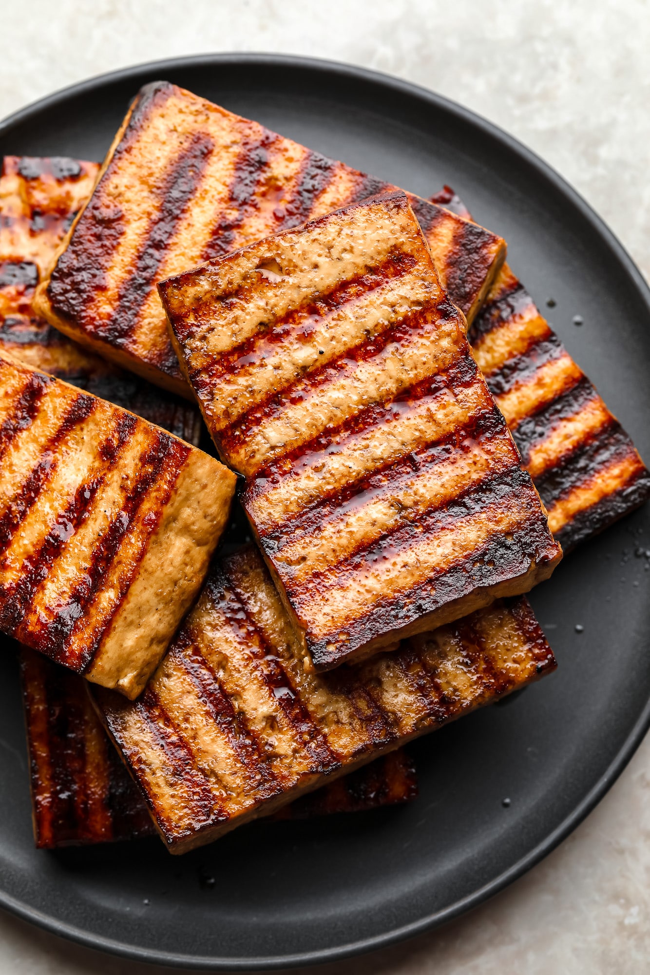 a pile of grilled tofu pieces on a black plate.