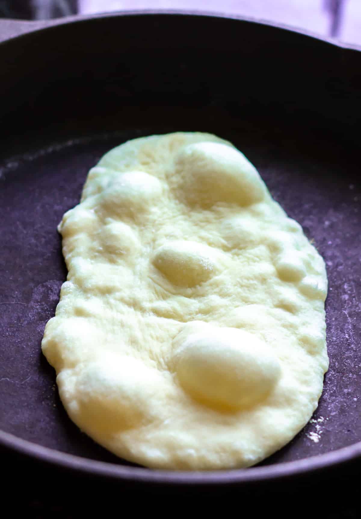 naan cooking on pan with bubbles