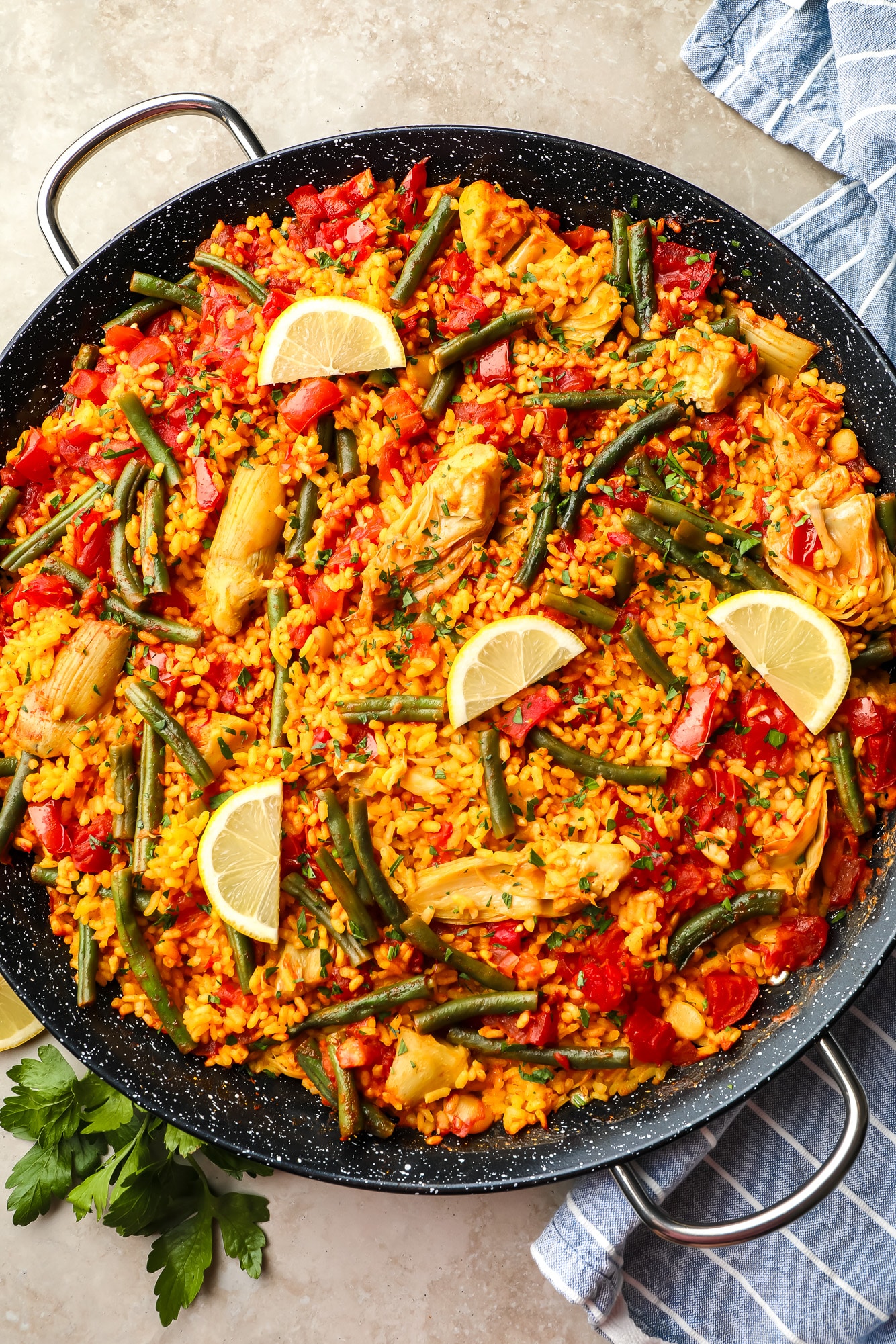 vegan paella topped with lemon slices in a large black paella pan.