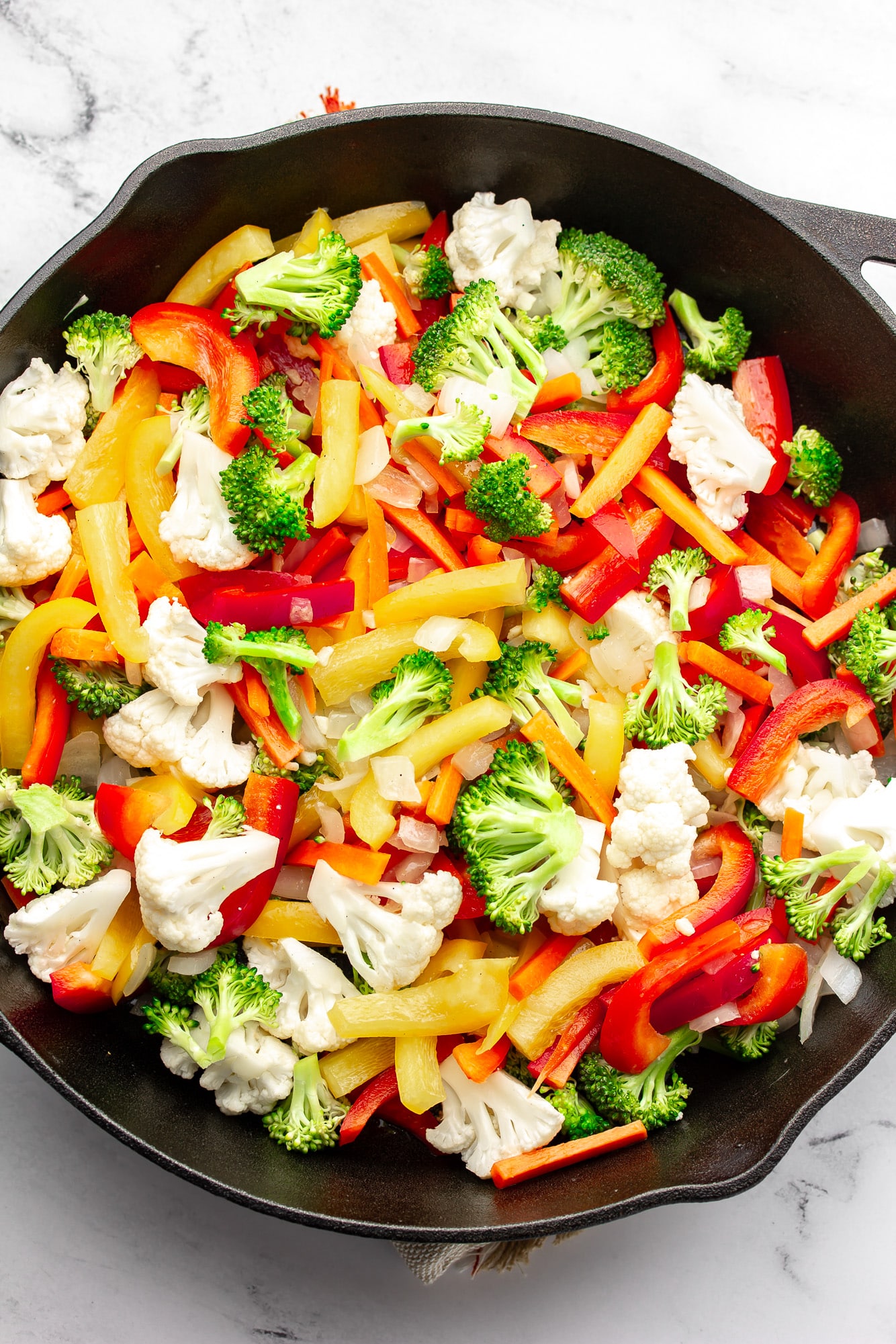 cooking chopped vegetables in a black skillet.