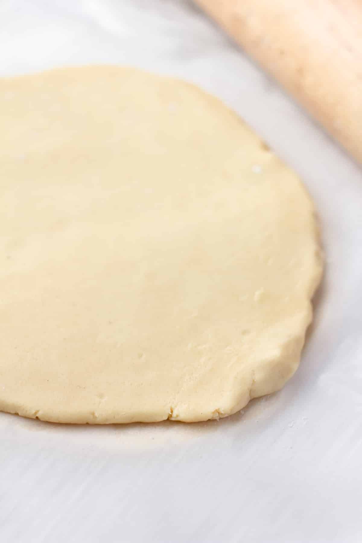 sugar cookie dough on parchment paper rolled out flat