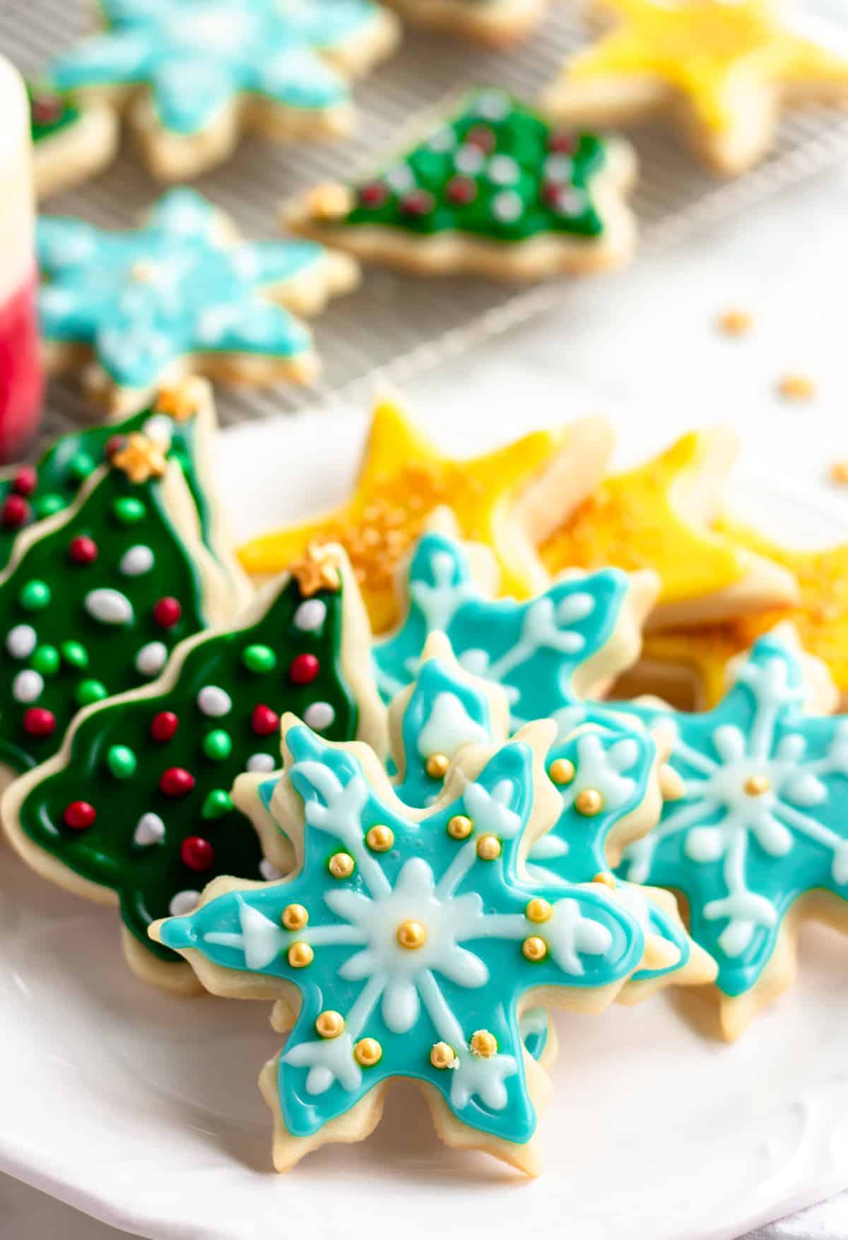 blue snowflake cookies and more vegan sugar cookies in the background on cooling rack