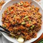 farro salad dressed in peanut sauce in a large white bowl with a gold spoon on the side.