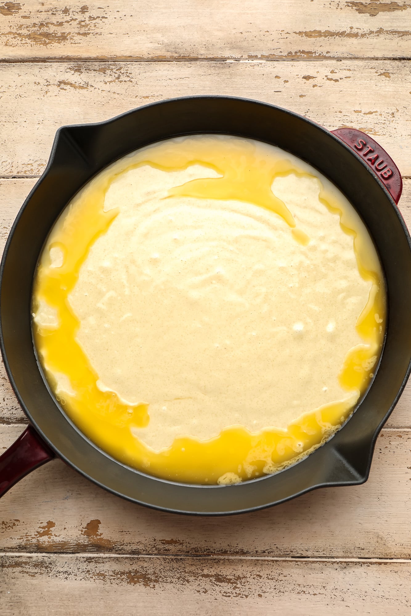 melted butter and cobbler dough in a black skillet.