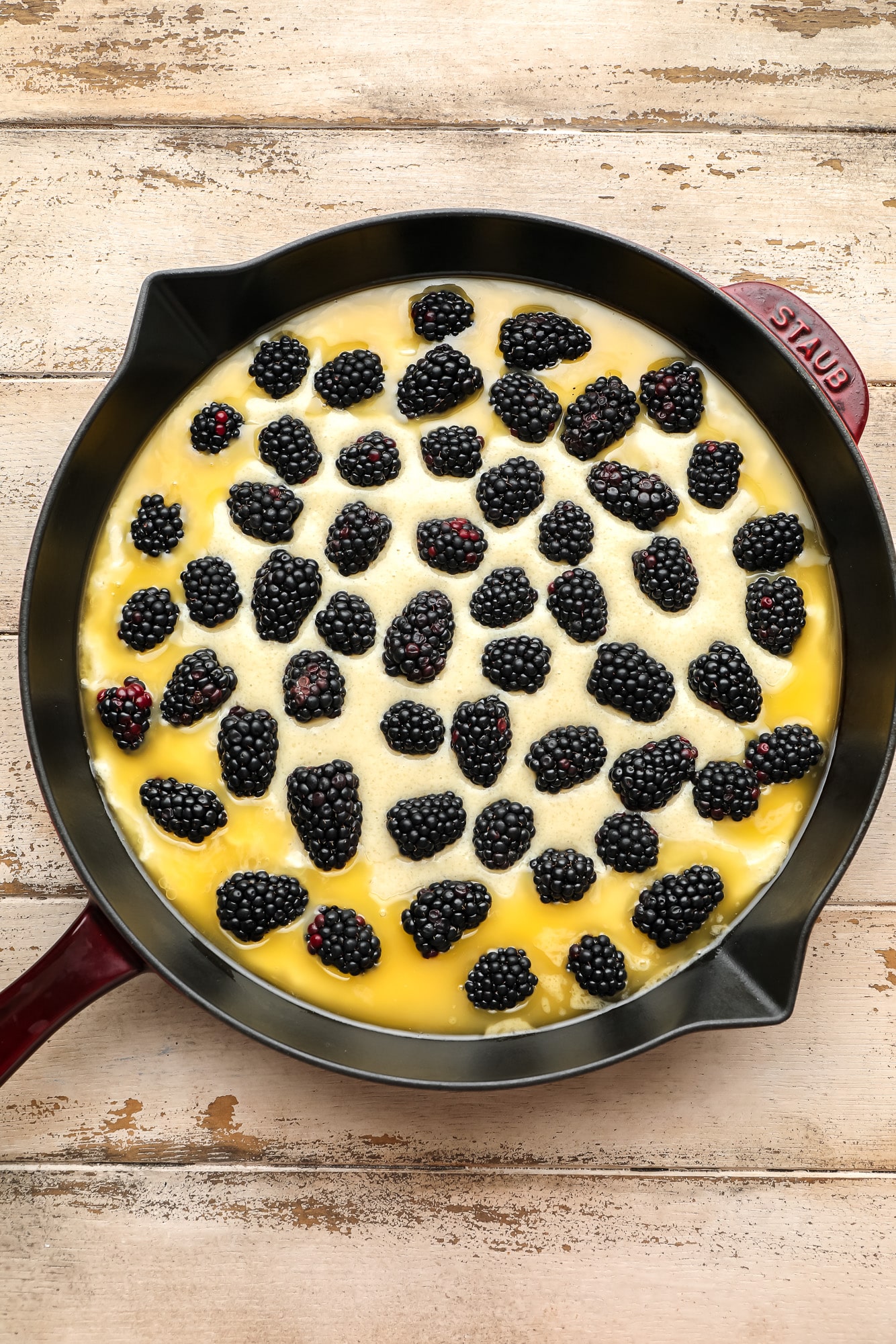 an unbaked and assembled blackberry cobbler in a black skillet.