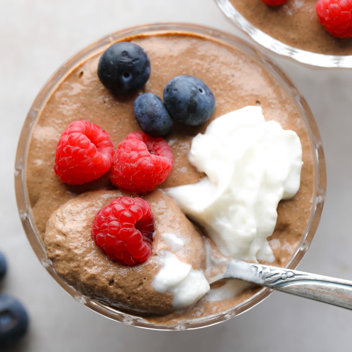 close up on a jar of chocolate chia pudding topped with berries and whipped cream.