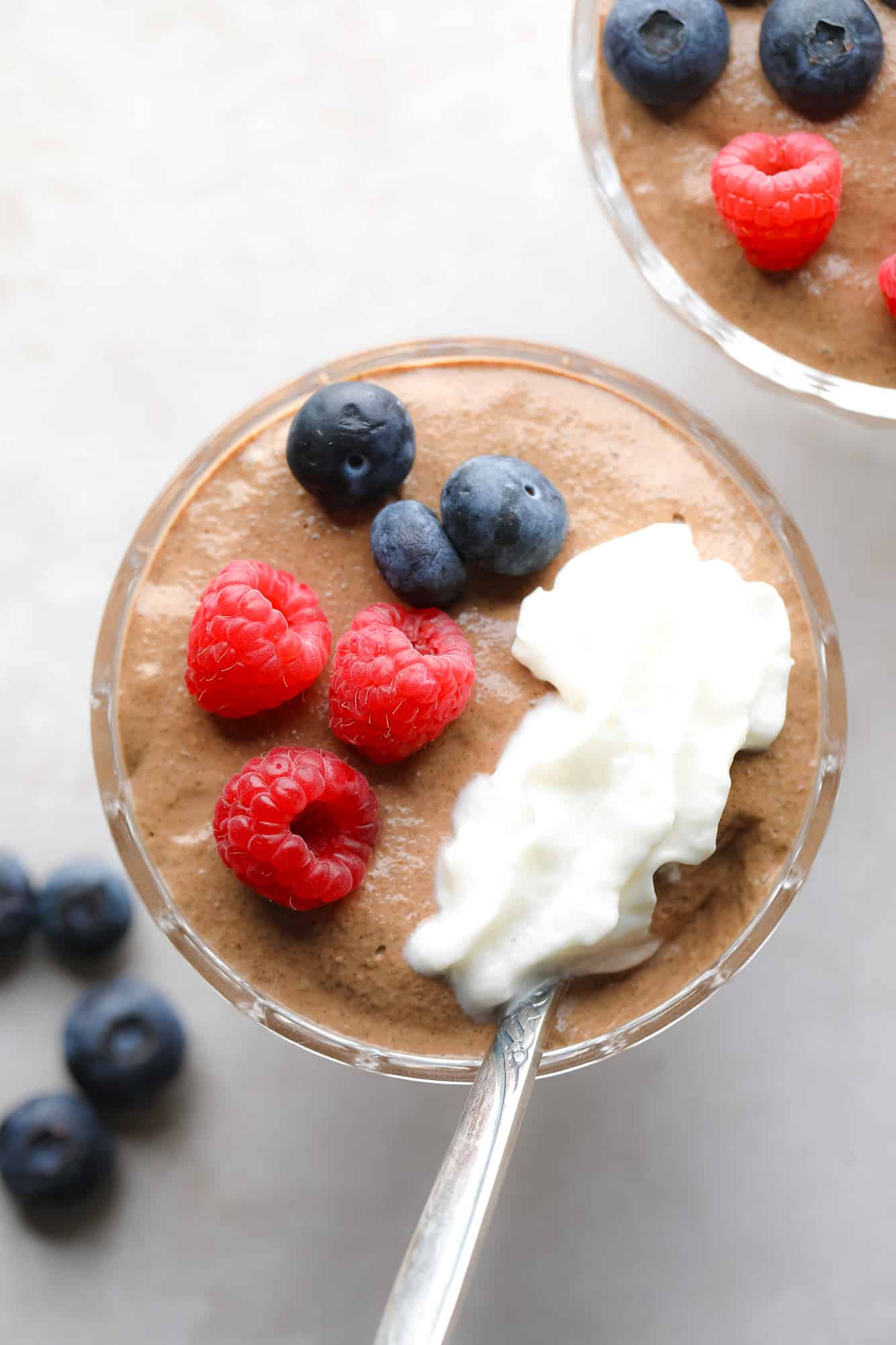 close up on a jar of chocolate chia pudding topped with berries and whipped cream.