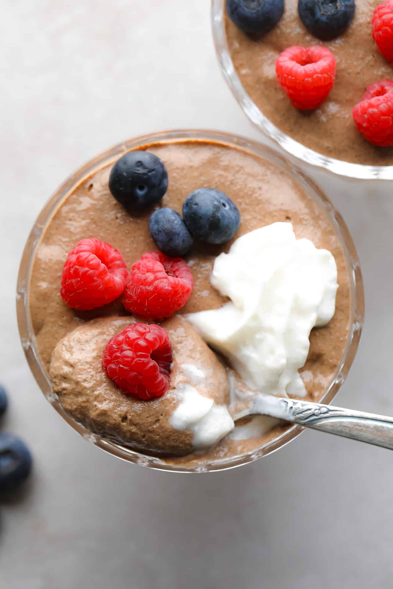 close up on a jar of chocolate chia pudding topped with berries and whipped cream.