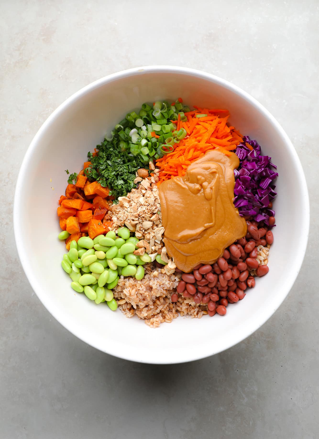 ingredients for farro salad and peanut sauce together in a large white bowl.