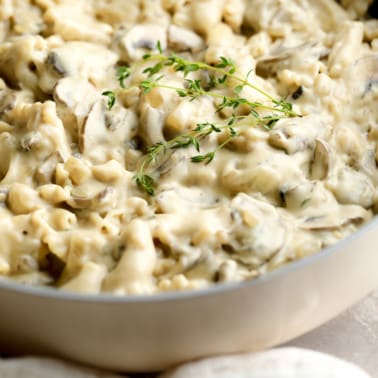 close up on vegan mushroom stroganoff topped with thyme in a pot.