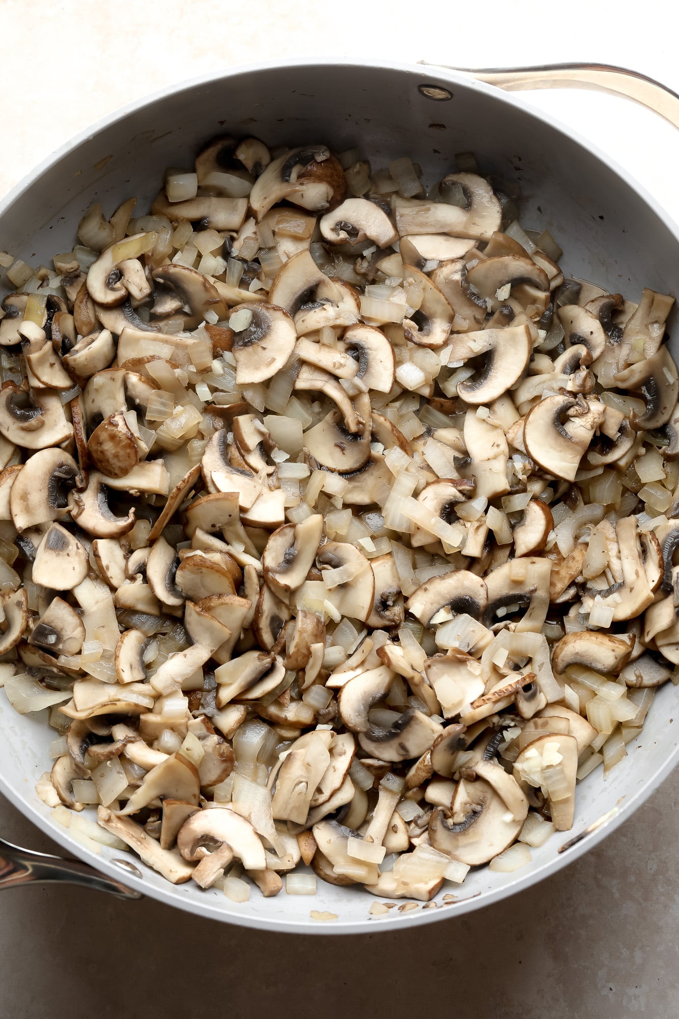 cooking sliced mushrooms and onions in a large grey pot.