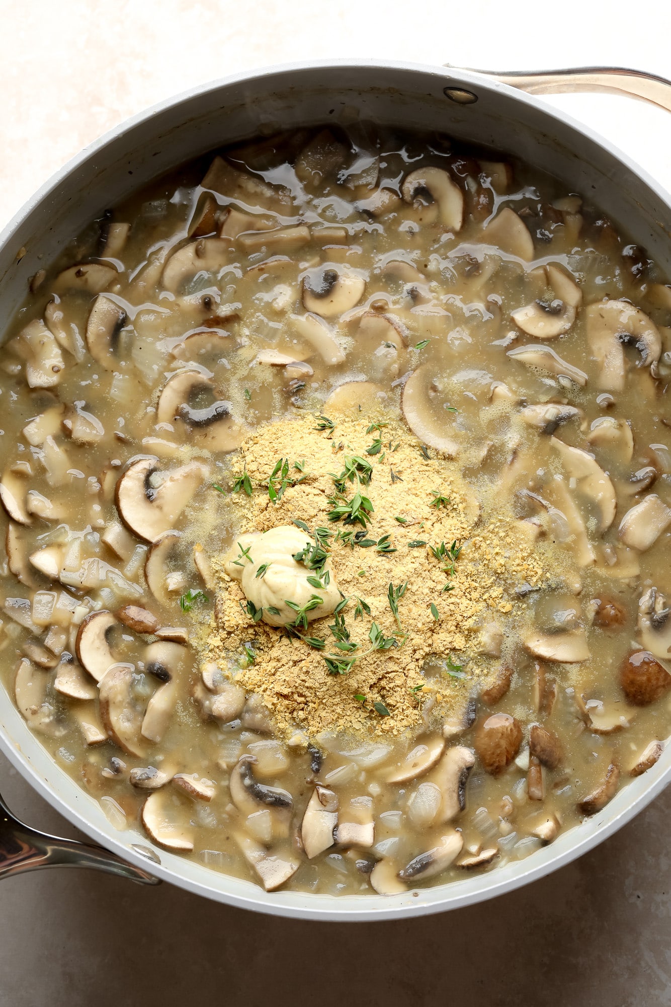 cooking the mushroom gravy for mushroom stroganoff in a large grey pot.