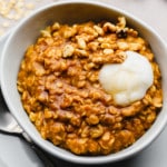 pumpkin oatmeal in a white bowl with a dollop of vegan yogurt on top.