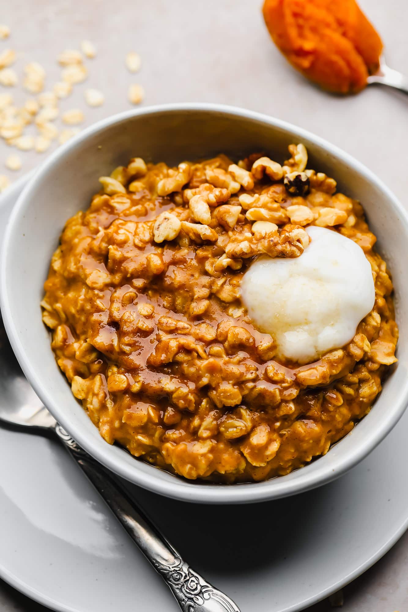 pumpkin oatmeal in a white bowl with a dollop of vegan yogurt on top.