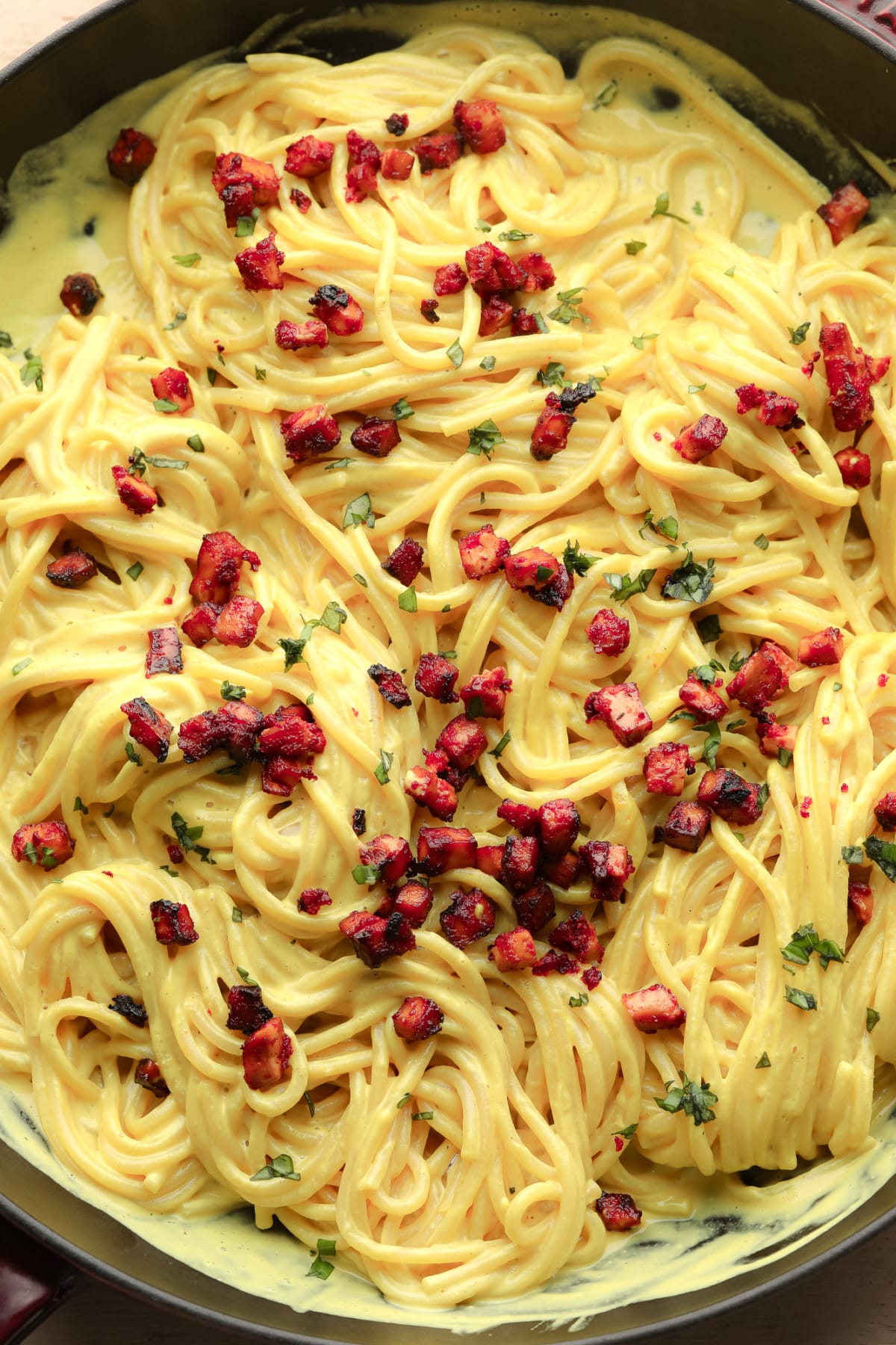 pan full of yellow spaghetti and reddish tofu pieces