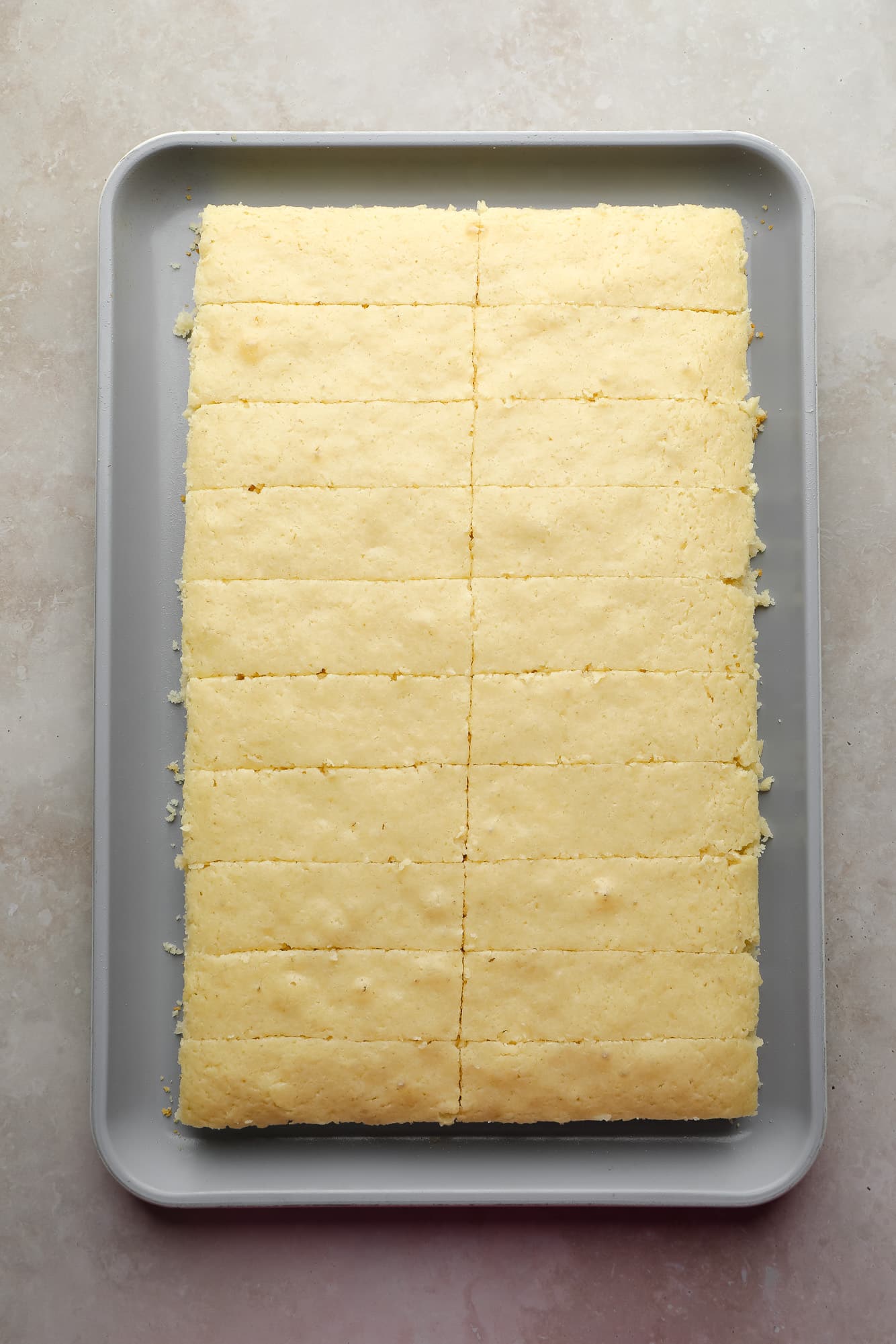 a vegan vanilla cake cut into strips on a sheet pan.