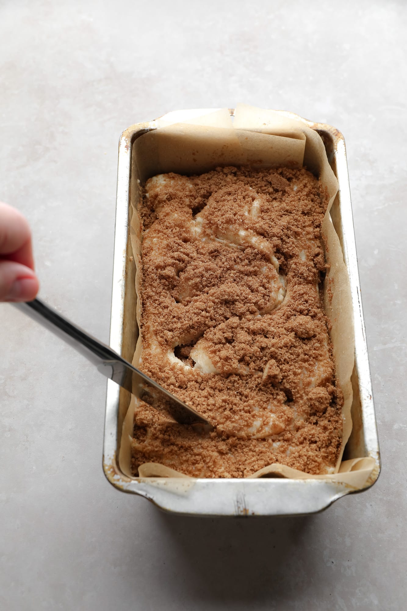 using a knife to make a swirl pattern in bread batter in a loaf pan.