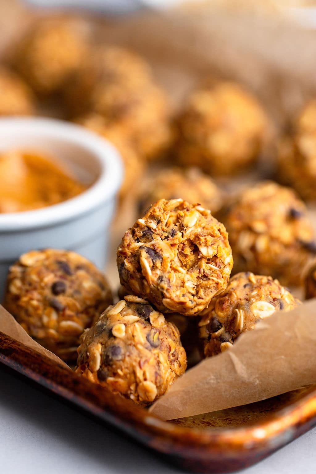 a peanut butter energy ball with a bite taken out of it on a parchment-lined baking sheet.