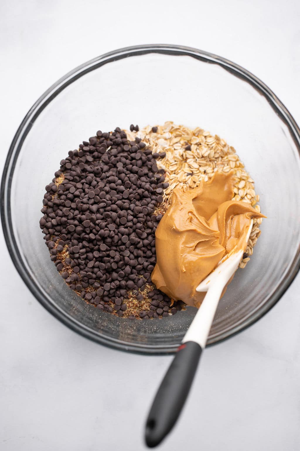 stirring the ingredients for Peanut Butter Energy Balls in a glass bowl.