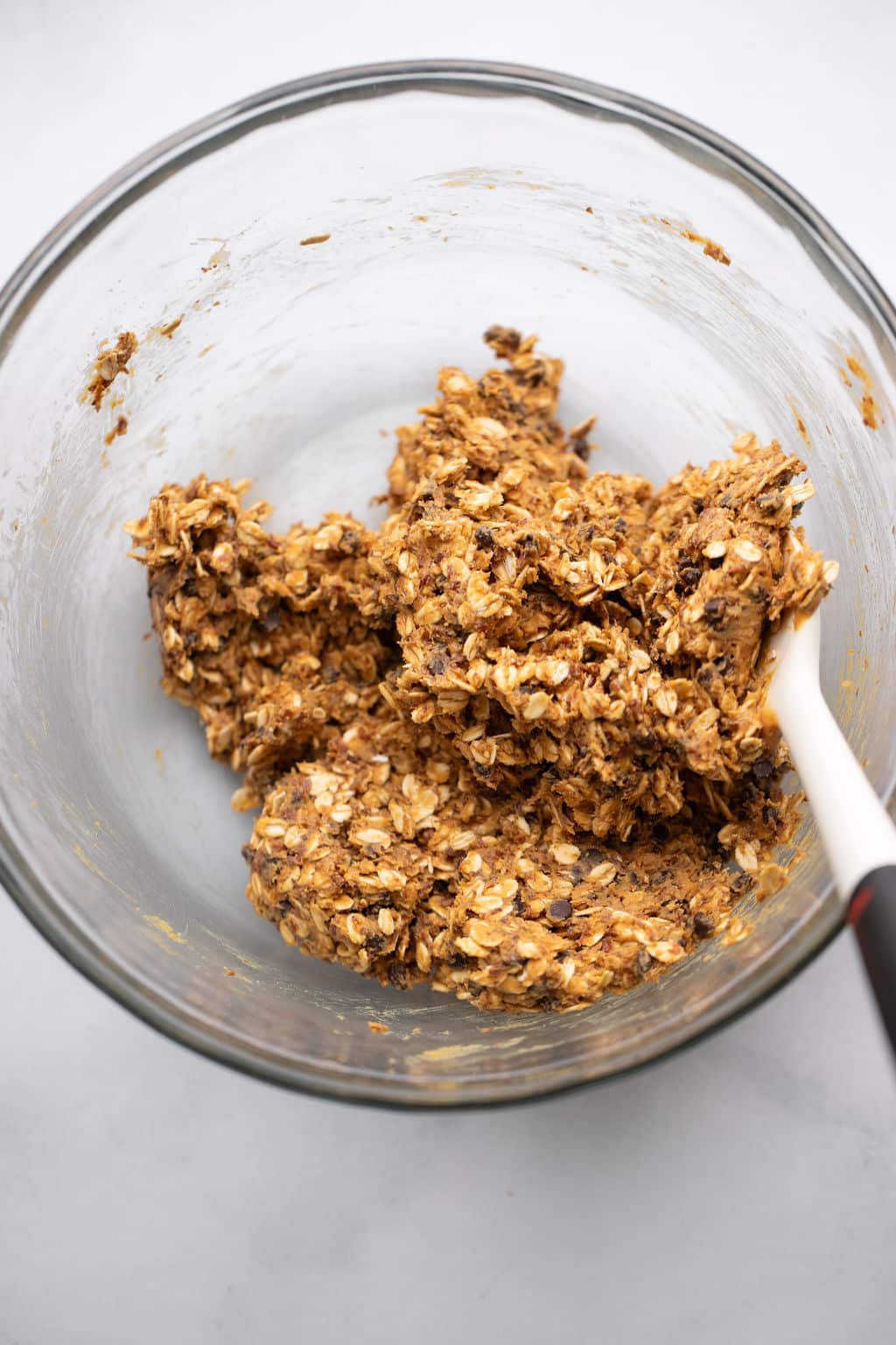 stirring the ingredients for Peanut Butter Energy Balls in a glass bowl.