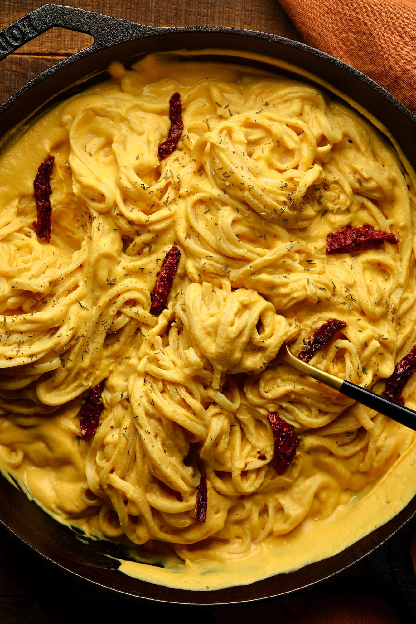 cast iron filled with long noodles with lots of butternut squash pasta sauce and sun dried tomatoes