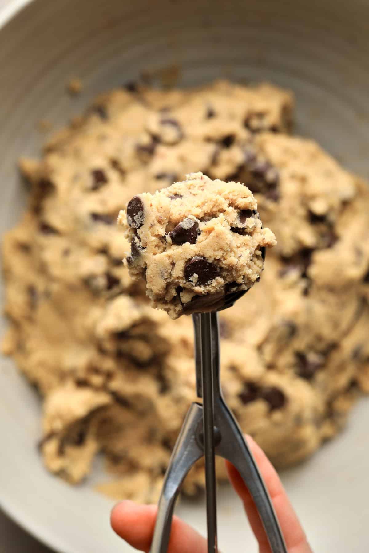 scooping cookie dough with scoop from large bowl