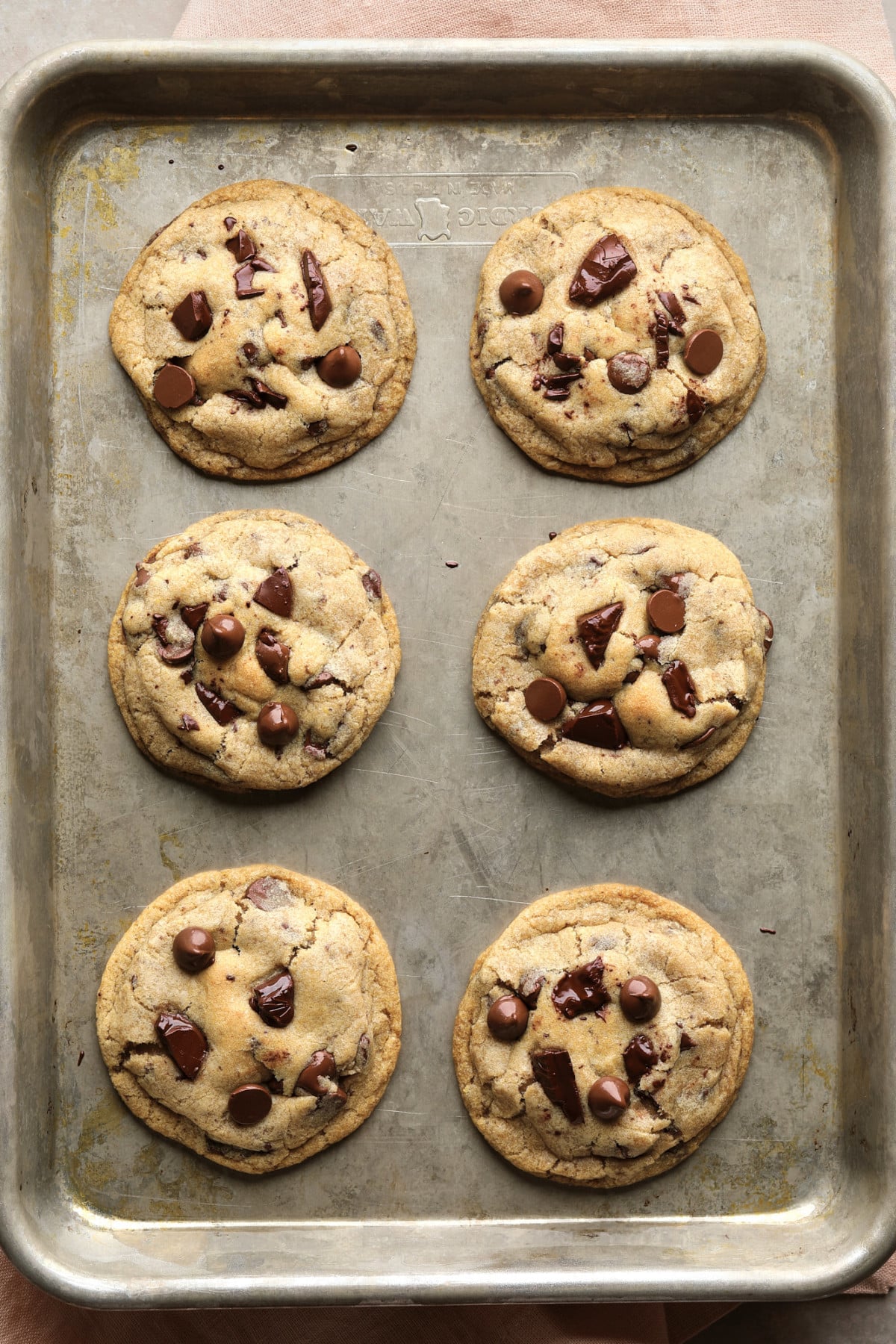 6 chocolate chip cookies on a baking sheet out of the oven