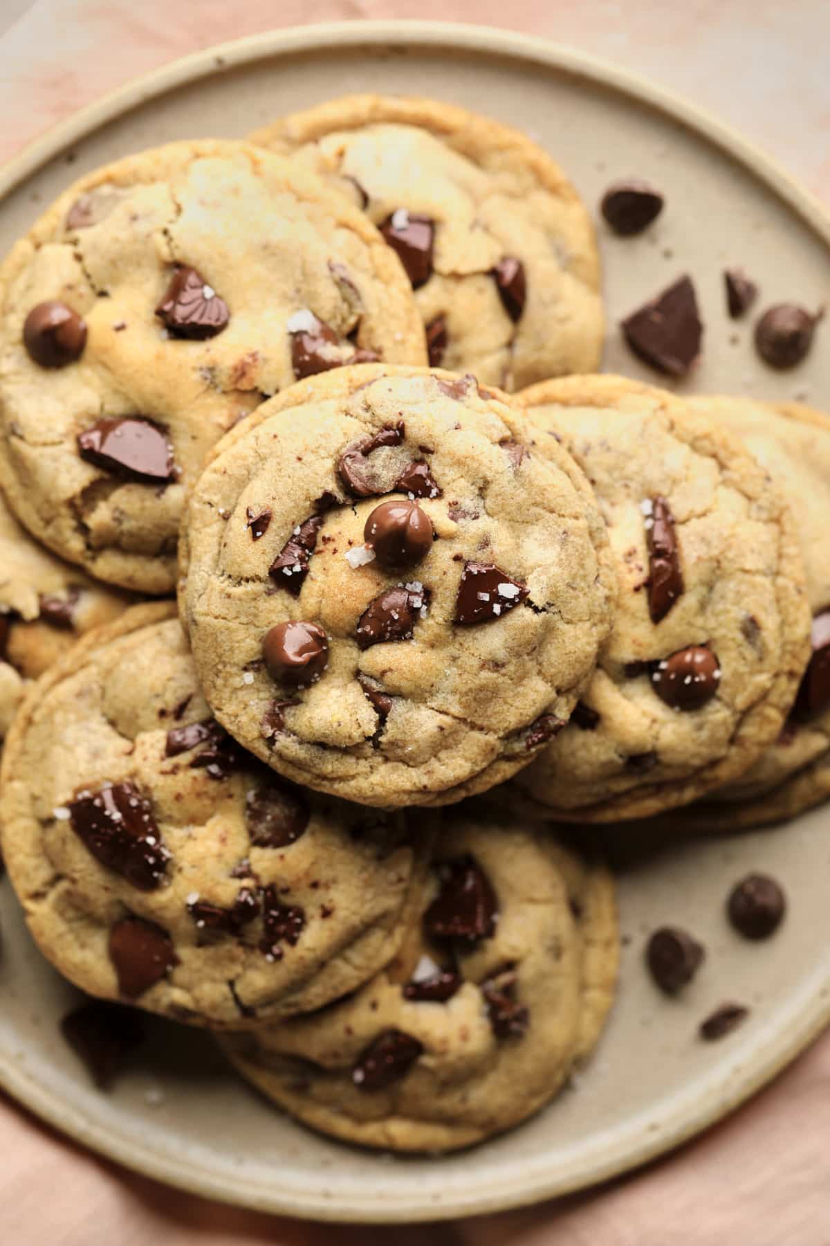 beige plate with many vegan chocolate chip cookies and pink towel