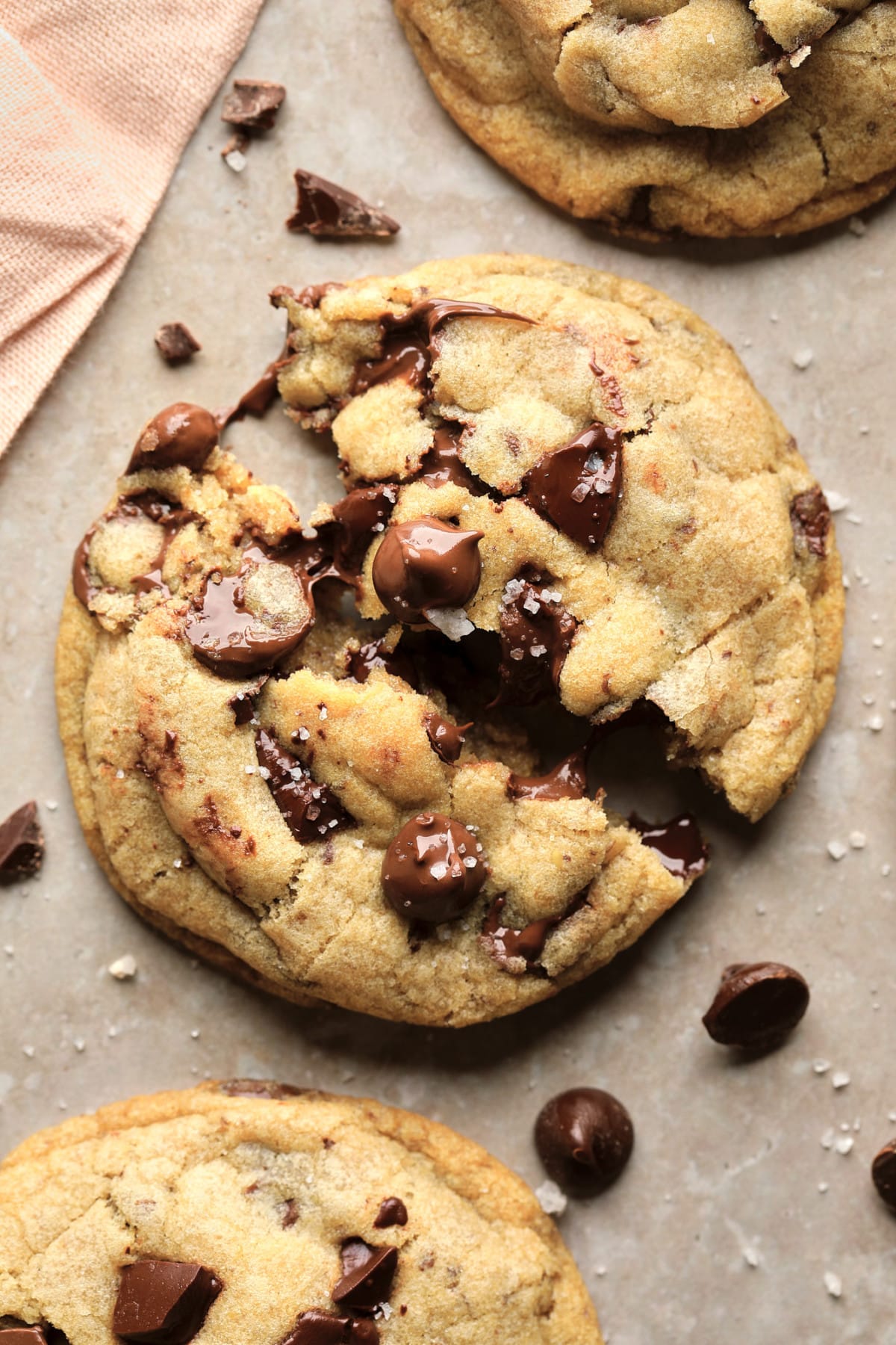 broken open chocolate chip cookie on beige background with coarse salt