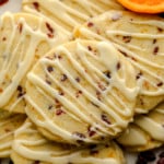 close up on a pile of Orange Cranberry Shortbread Cookies decorated with orange glaze.