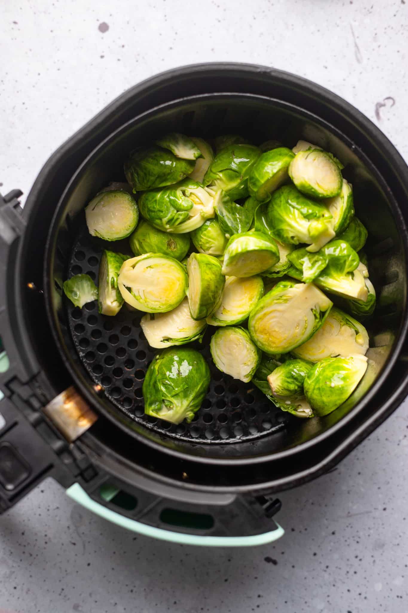 halved brussels sprouts in an air fryer basket.