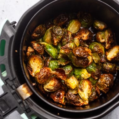 cooked brussels sprouts in an air fryer basket.